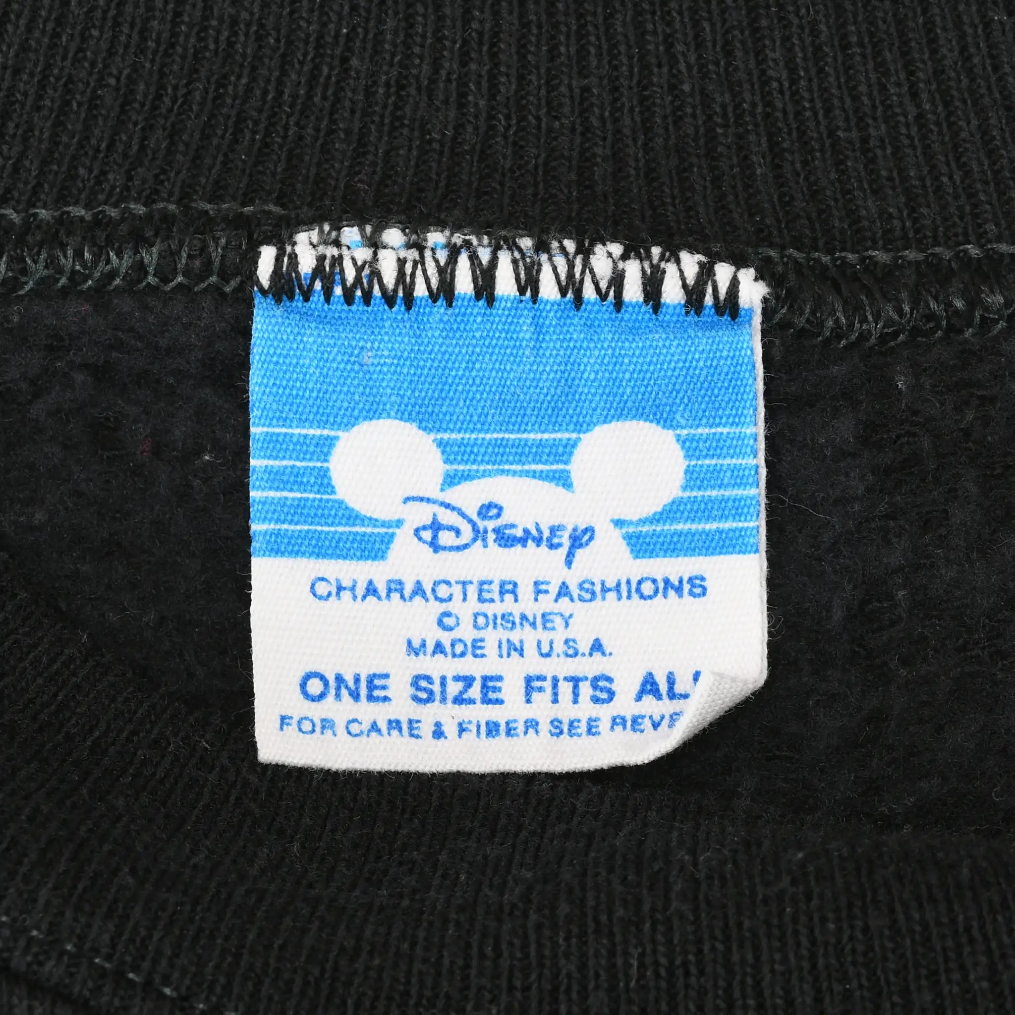 Close-up of Disney Character Fashions neck label marked One Size Fits All and Made in U.S.A.