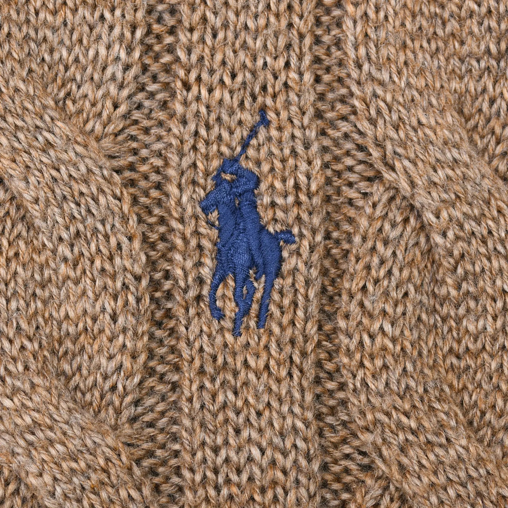 Close-up of blue Polo pony embroidery on brown cable-knit sweater