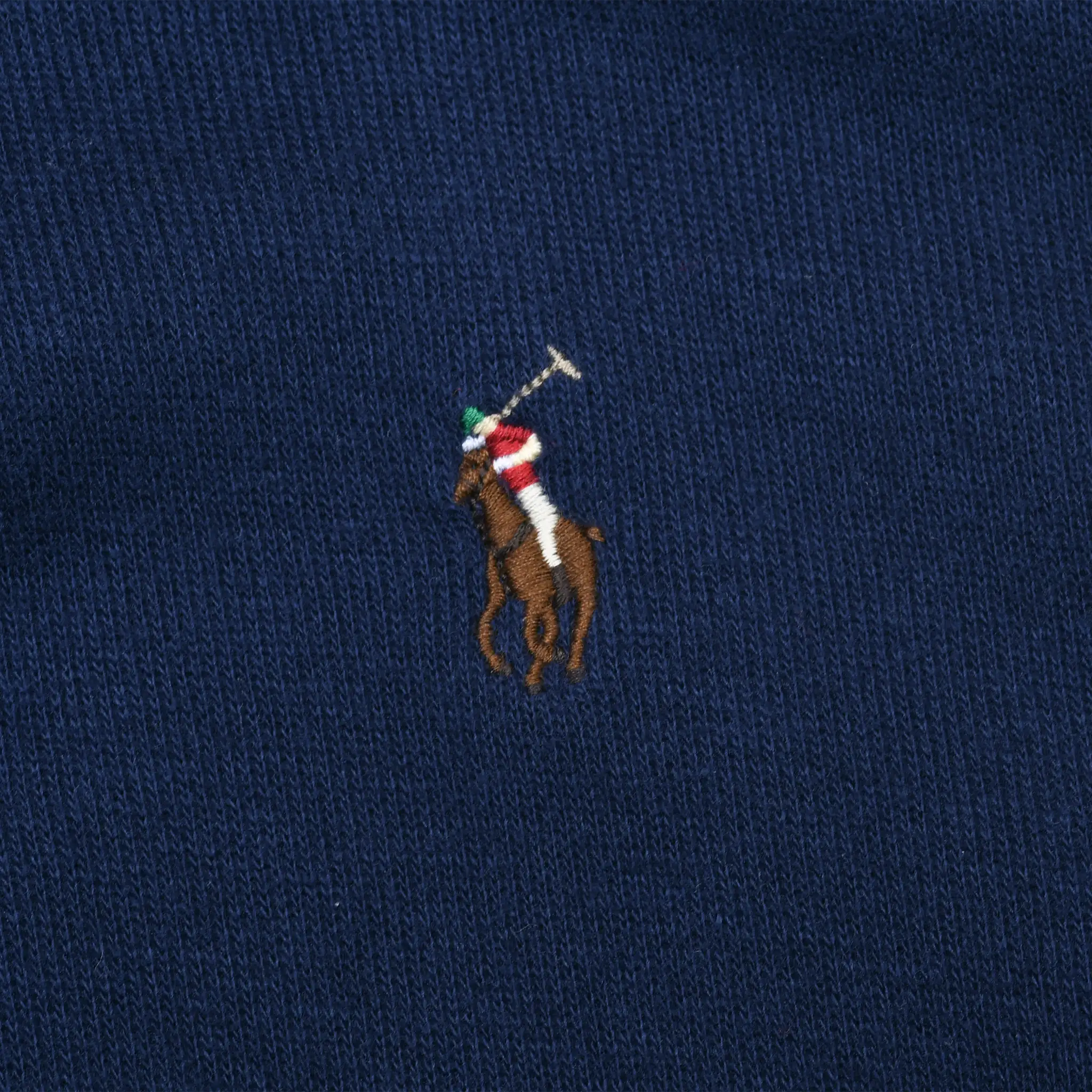Close-up of multicolor Polo pony embroidery on navy blue sweater