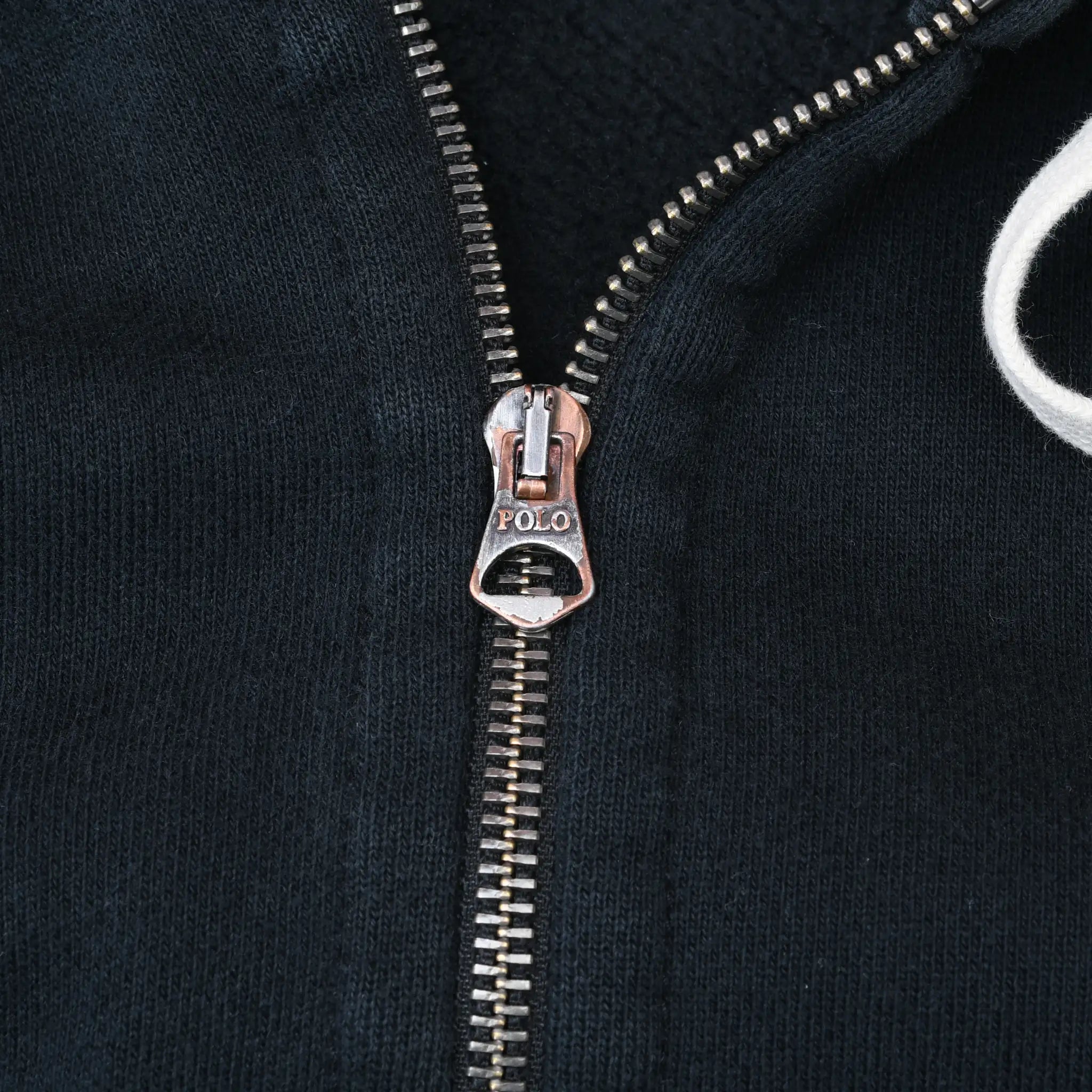 Close-up of Polo-branded metal zipper pull on black hoodie