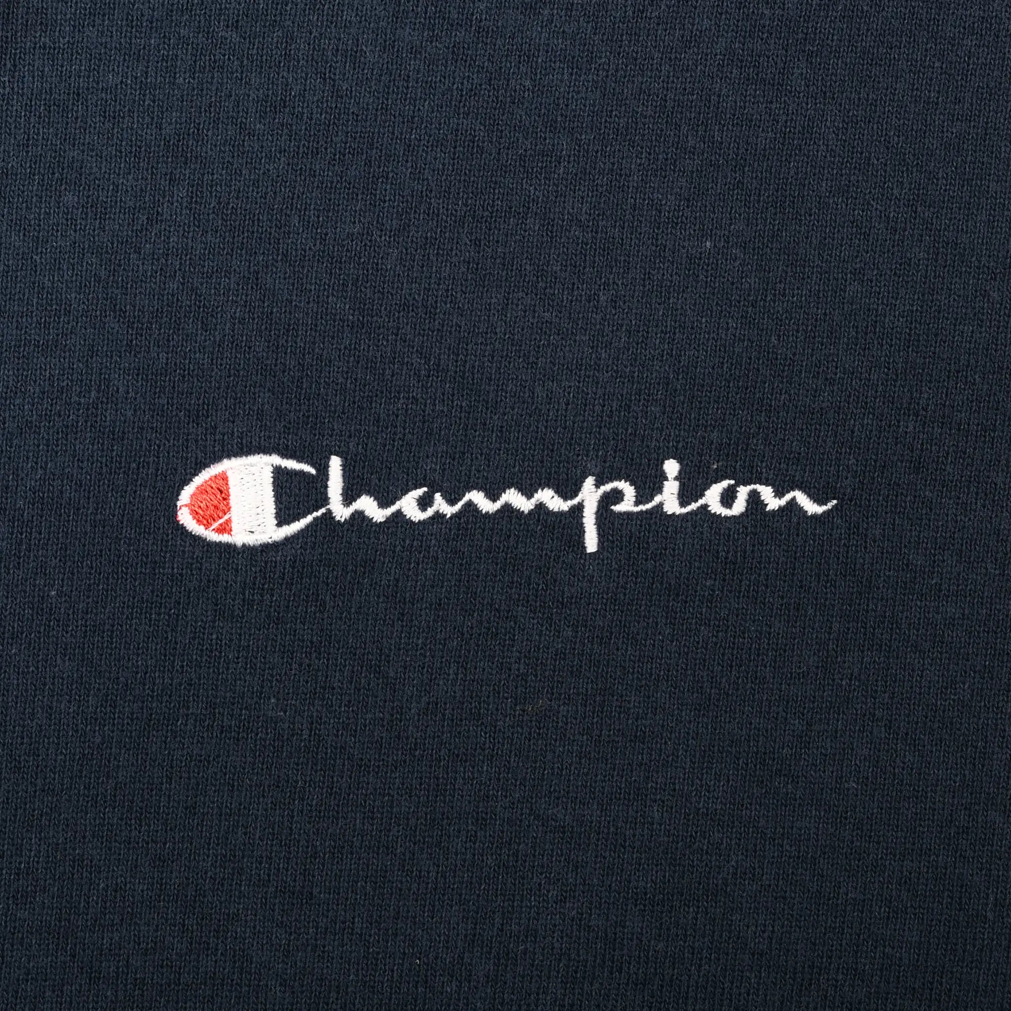 Close-up of small white, red, and blue Champion chest embroidery