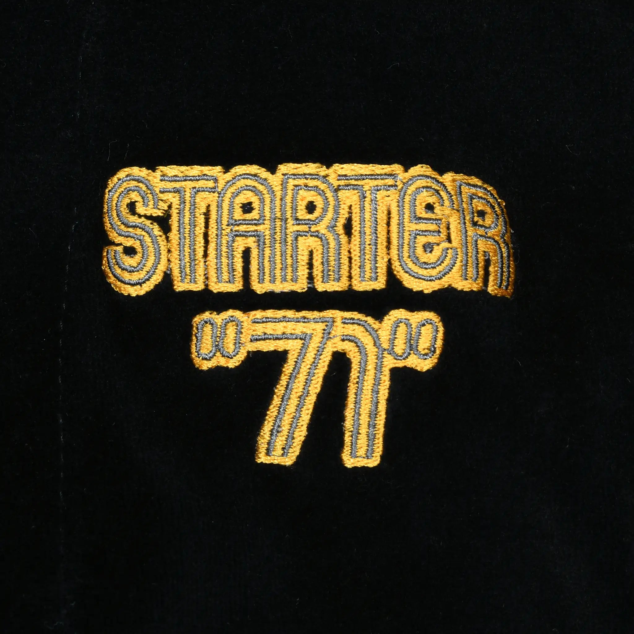 Close-up of gold and gray Starter 71 chest embroidery on black velvet