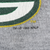 Close-up of copyright print and cracked Green Bay Packers logo on gray sweatshirt fabric