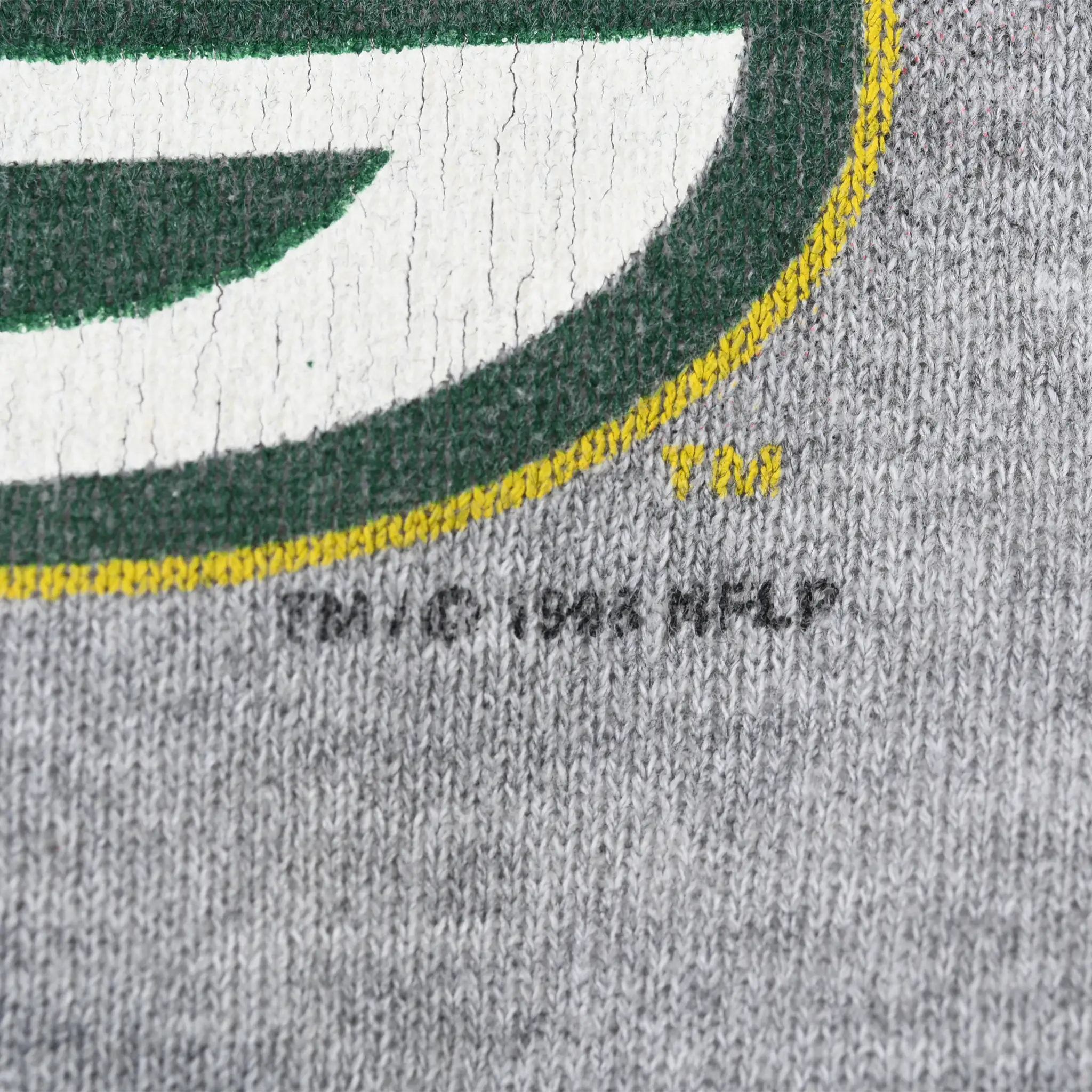 Close-up of copyright print and cracked Green Bay Packers logo on gray sweatshirt fabric