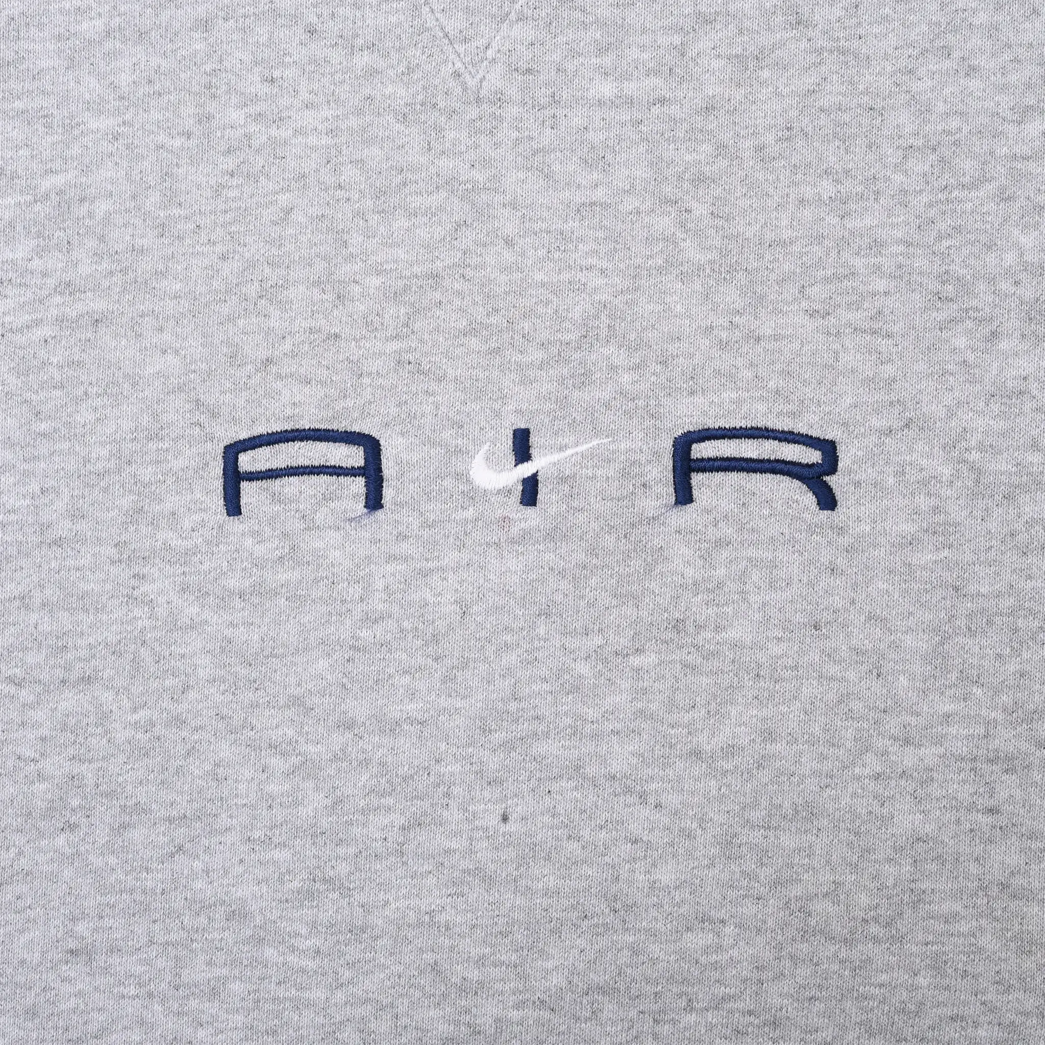 Close-up of navy Air lettering and white Nike Swoosh embroidery on grey fabric