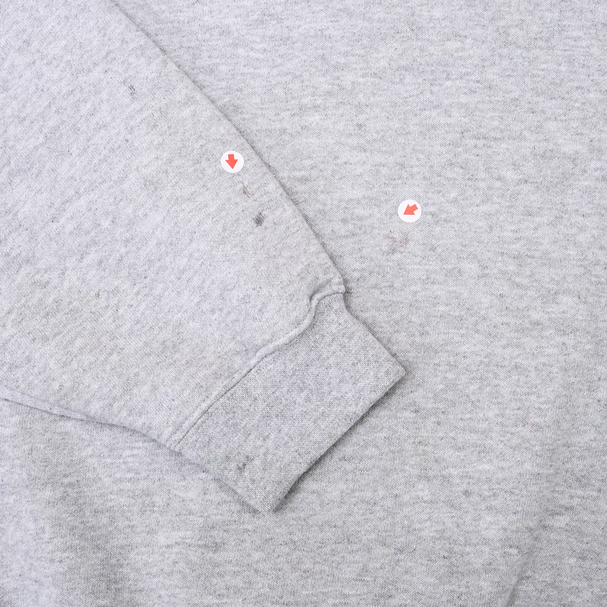 Close-up of grey sleeve cuff and small marked spots on the fabric