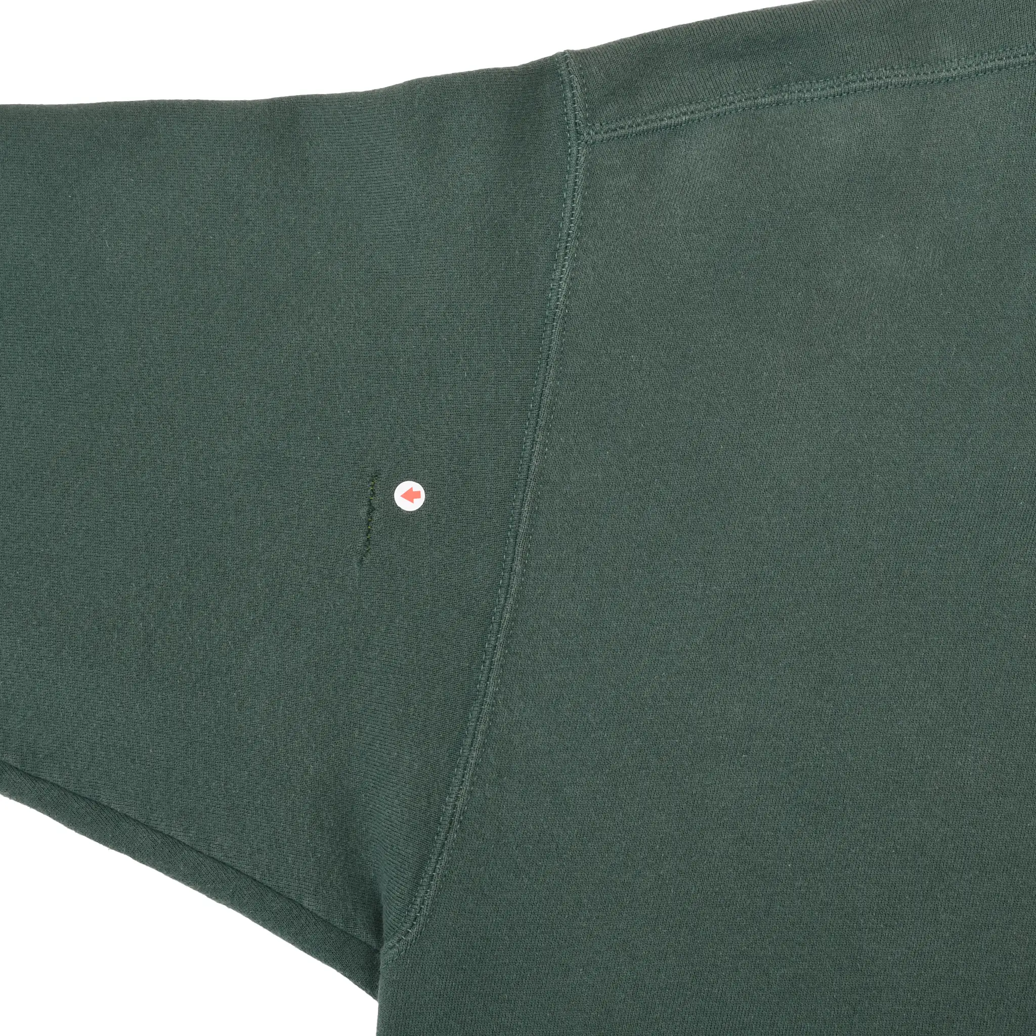 Close-up of small hole marked near the underarm seam of green Nike hoodie
