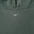Close-up of small white Nike Swoosh embroidered at the center chest of green hoodie