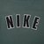 Close-up of large black NIKE lettering with white outlines on back of green hoodie