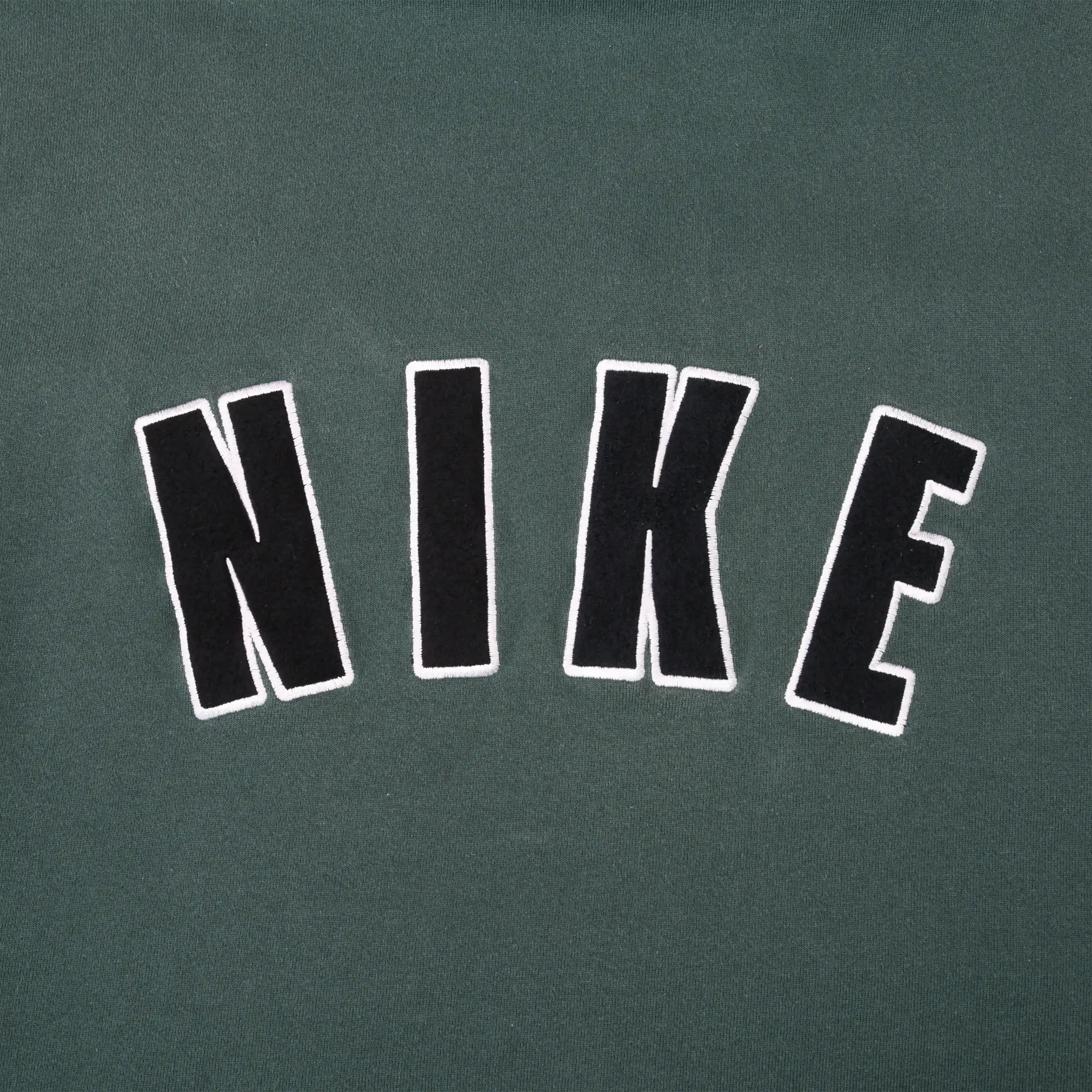Close-up of large black NIKE lettering with white outlines on back of green hoodie