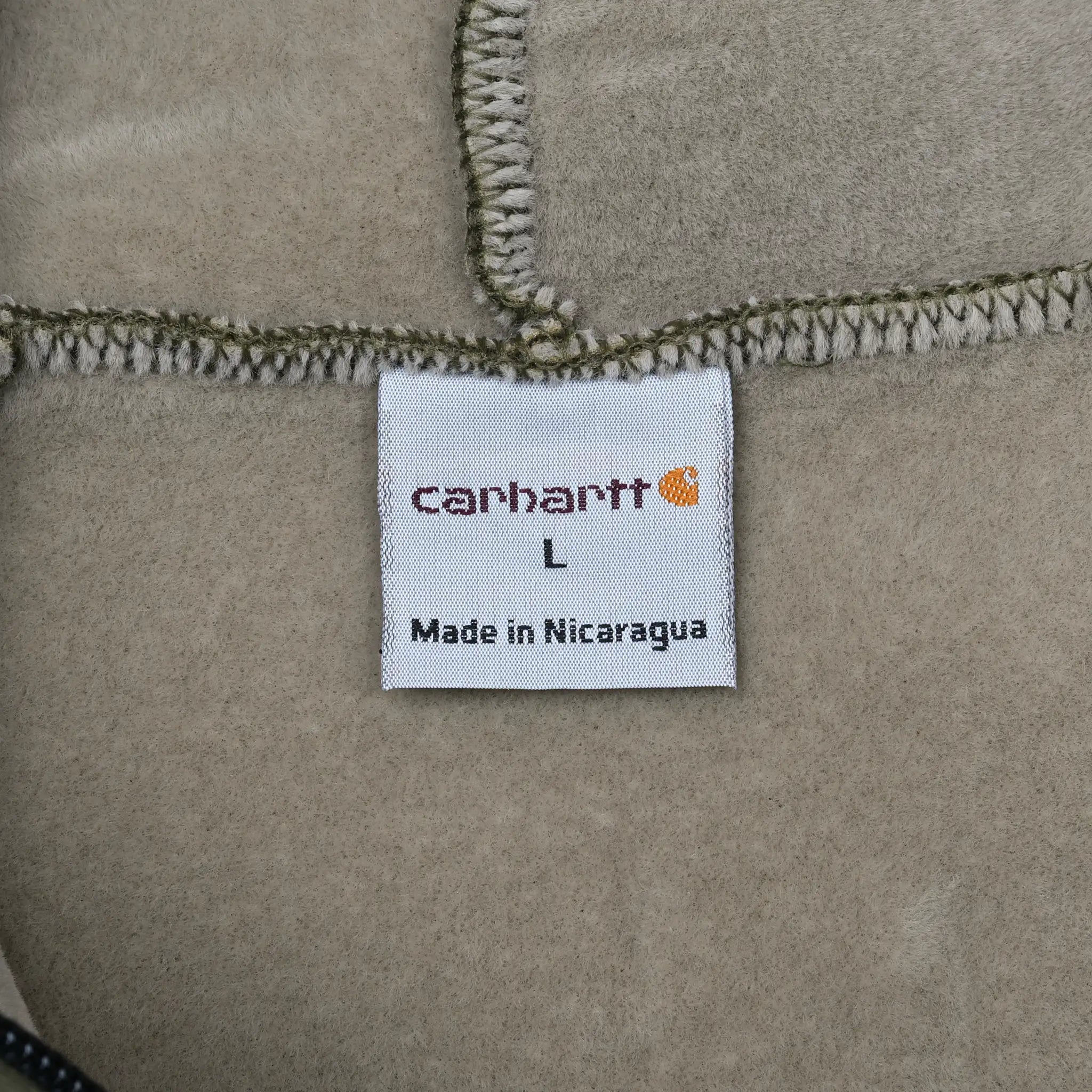 Carhartt interior label marked size L and Made in Nicaragua against beige fleece lining