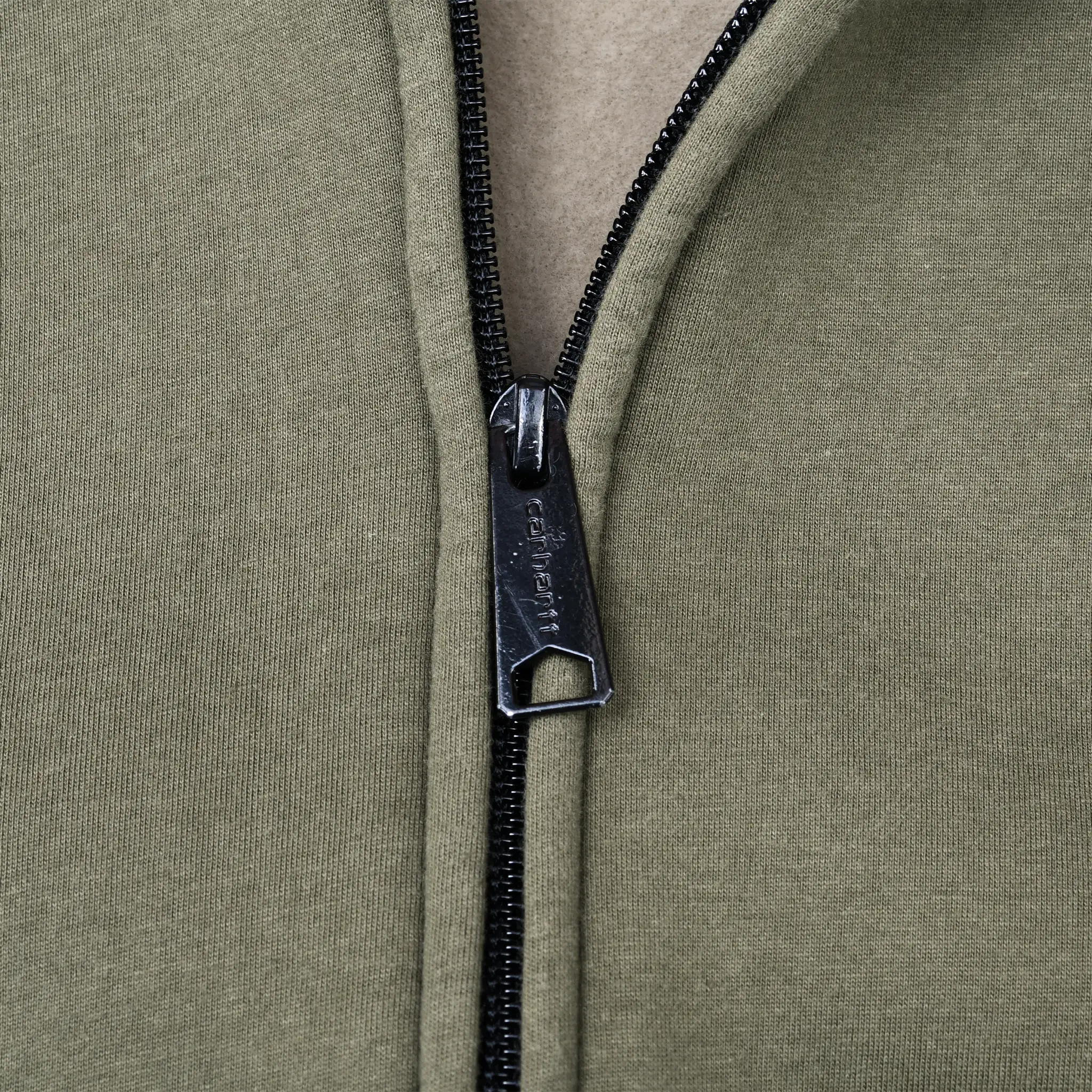 Close-up of black Carhartt zipper pull and olive green hoodie fabric