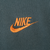 Close-up of orange Nike Swoosh embroidery on sage green sweatshirt